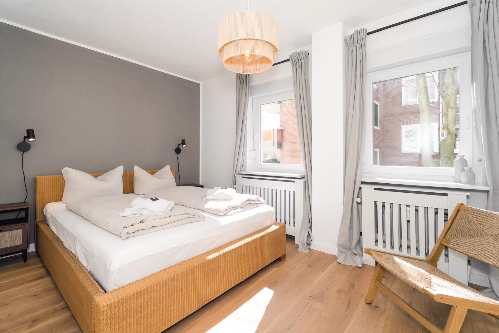 Schlafzimmer mit Doppelbett und großen Fenstern