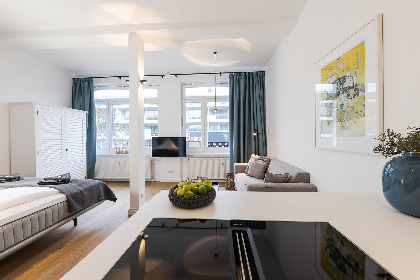 Offener Wohnraum mit Bett, Säule und Küchenzeile